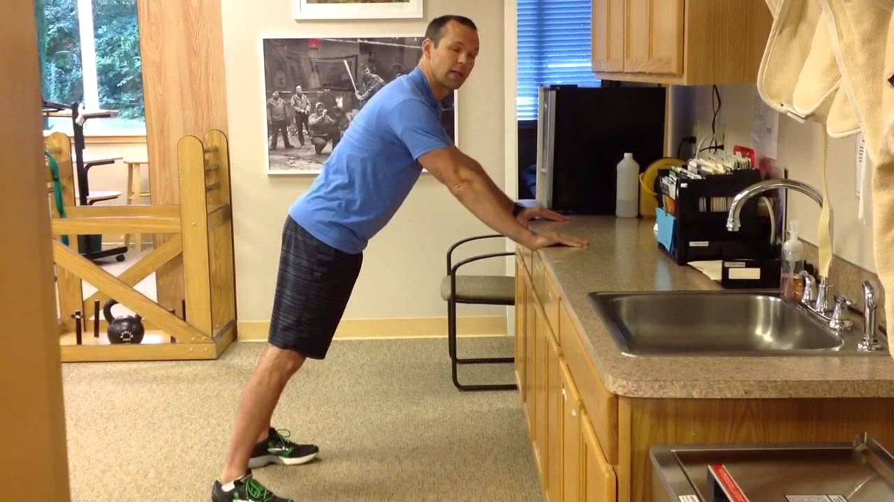 A beginner doing an incline push-up with hands on a kitchen counter, body in a straight line