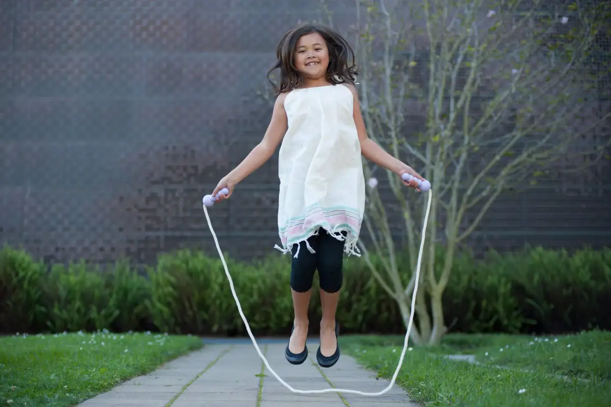 A beginner doing small, controlled basic bounce jumps with a jump rope on a driveway