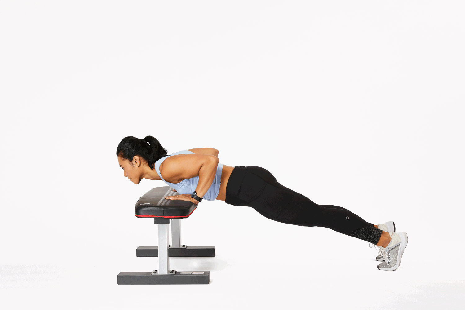 A person doing a close-grip incline push-up with hands on the seat of a chair, elbows bending back and body in a straight line