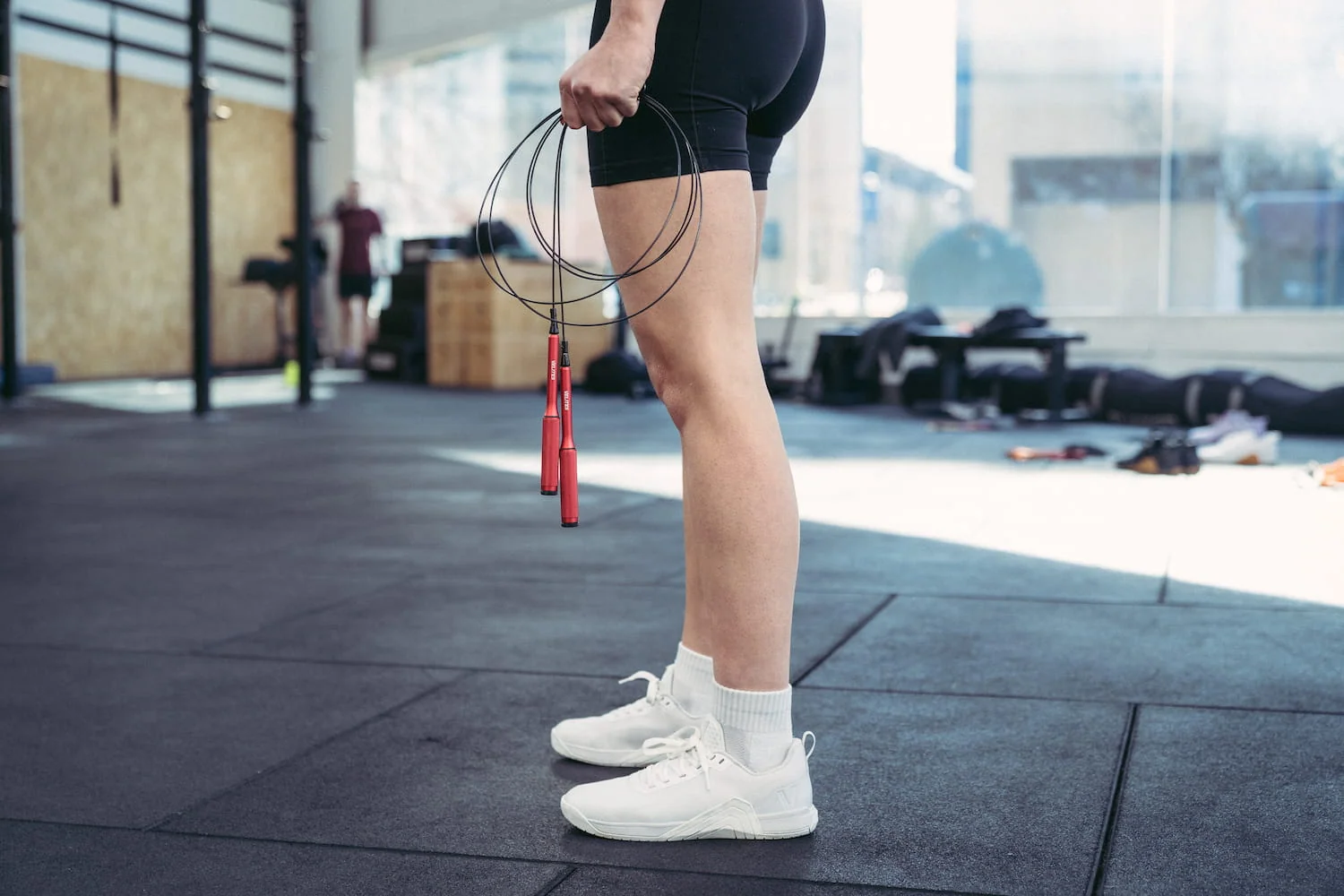 A person doing high knees with a jump rope on a driveway, knees lifting while the rope clears underfoot