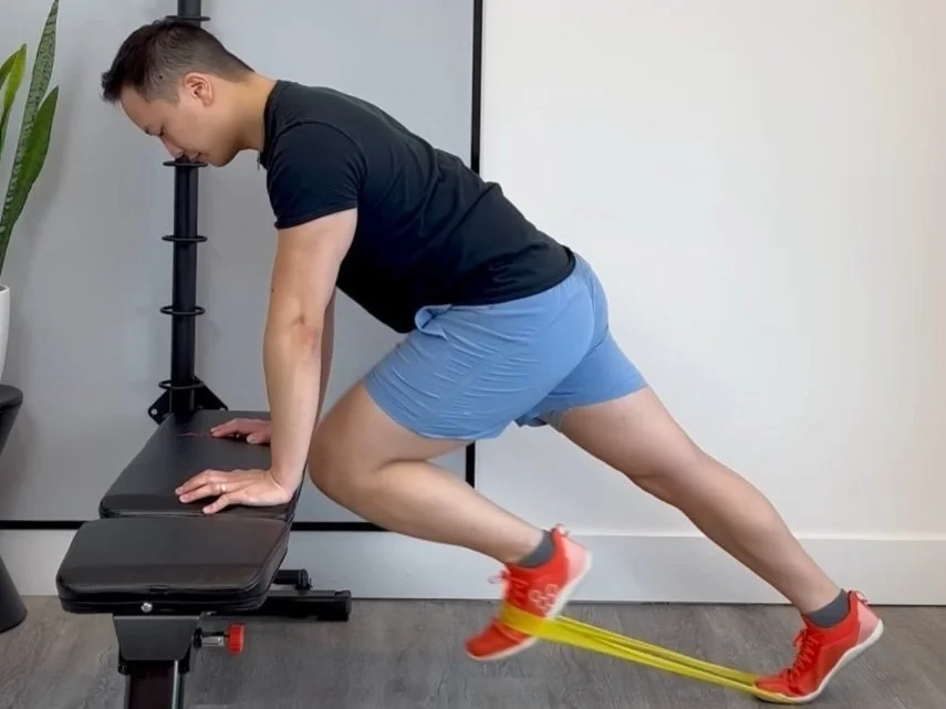 A person doing incline mountain climbers with hands on the edge of a couch in a small apartment living room, neutral lighting