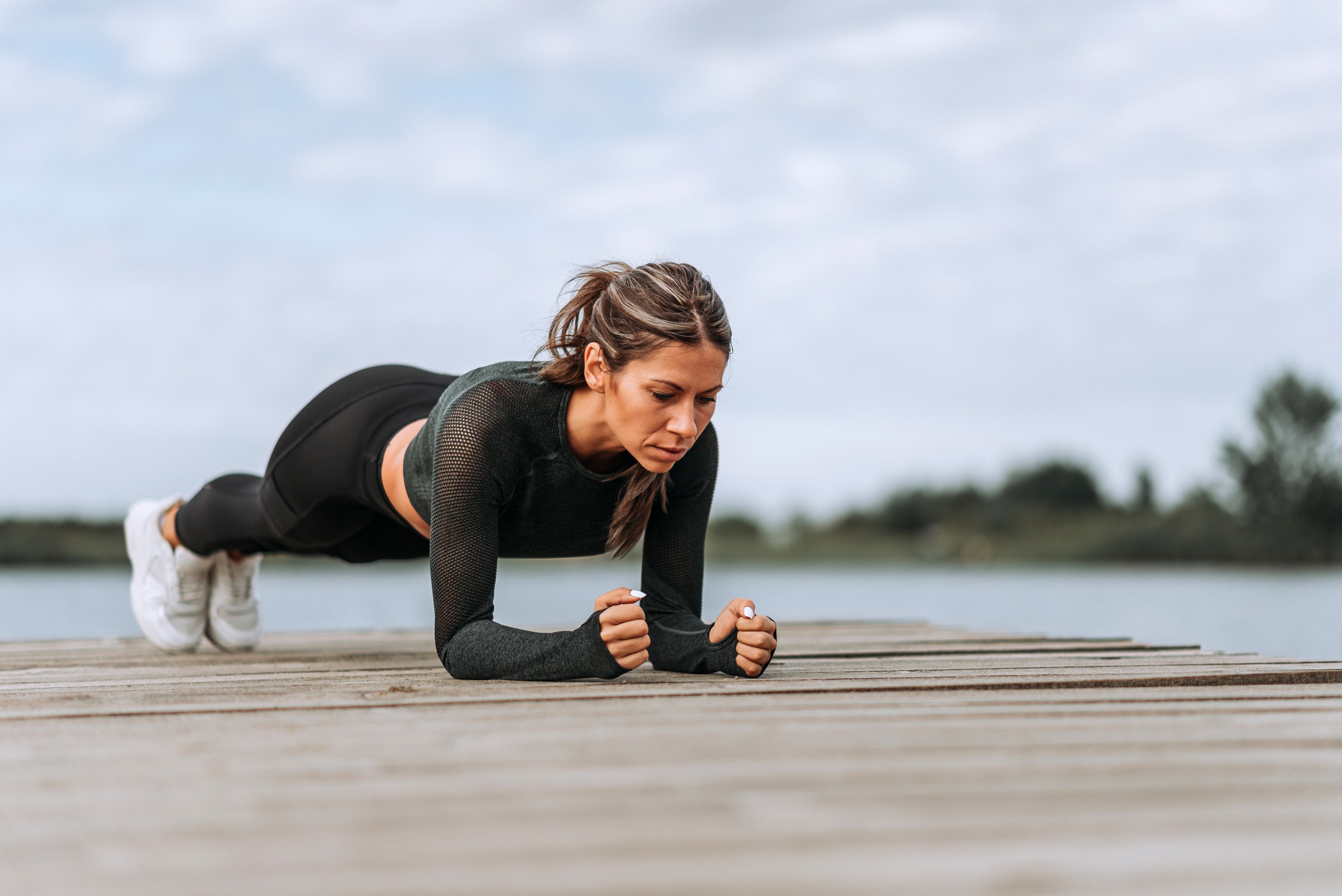 A person holding a forearm plank on a yoga mat with hips level and glutes engaged, showing a straight line from shoulders through hips to heels