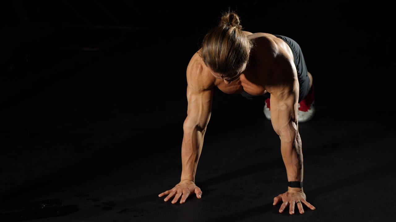 A person in a high plank position performing a scapular push-up with elbows straight while shoulder blades glide apart and together