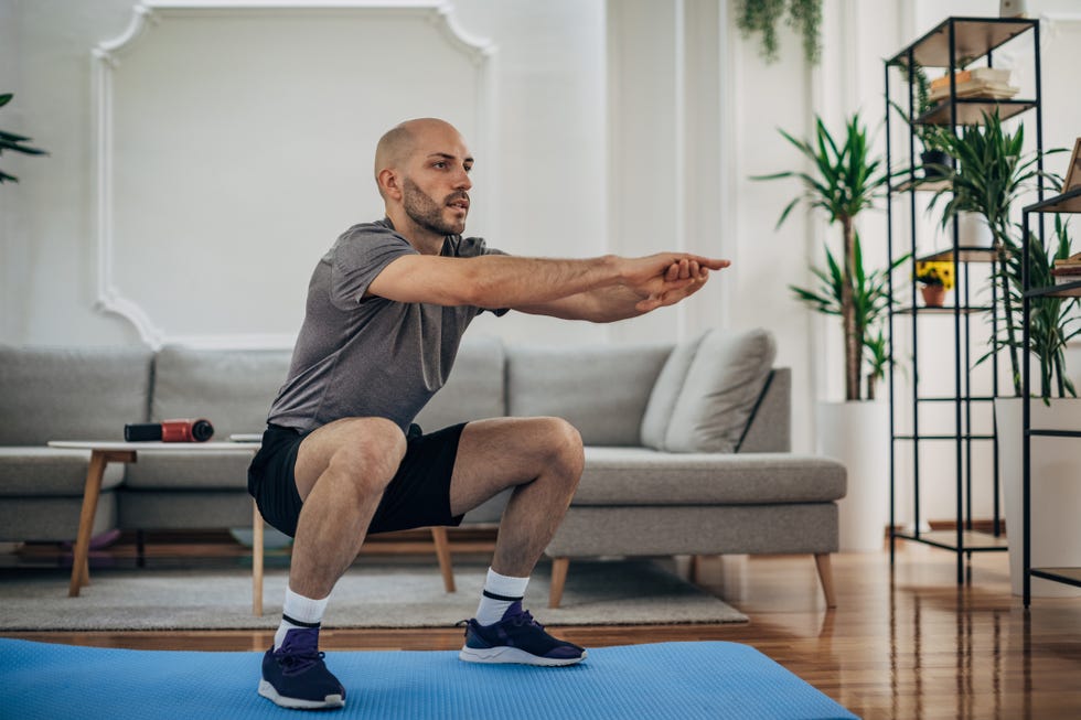 A person performing a controlled bodyweight squat with stable feet and an upright torso