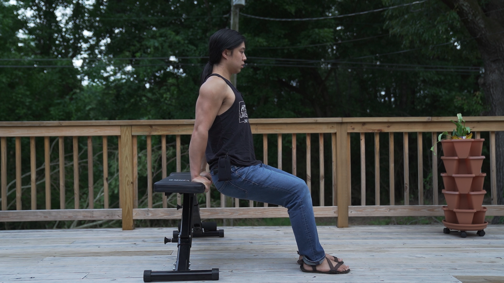 A person set up for chair dips with knees bent and feet flat, hips just off the chair, shoulders down and elbows pointing back