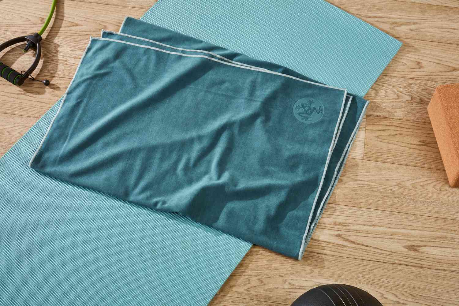 A rolled yoga mat next to a folded towel on a hardwood floor, ready to be used as knee padding for mobility exercises