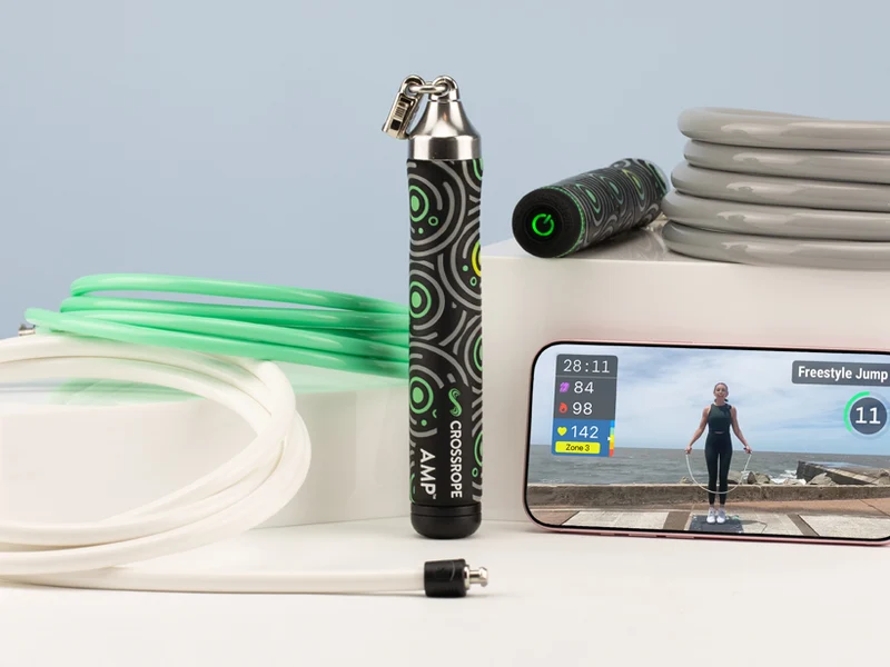 A smartphone interval timer on the ground beside a jump rope and water bottle on a driveway