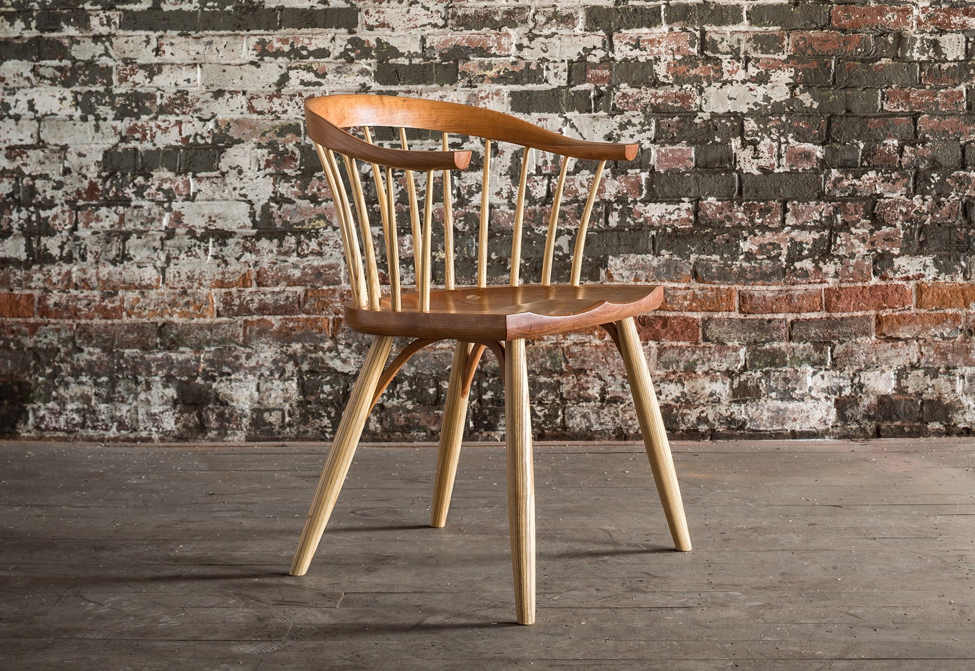 A sturdy dining chair pushed against a wall with a yoga mat under the chair legs on a hardwood floor