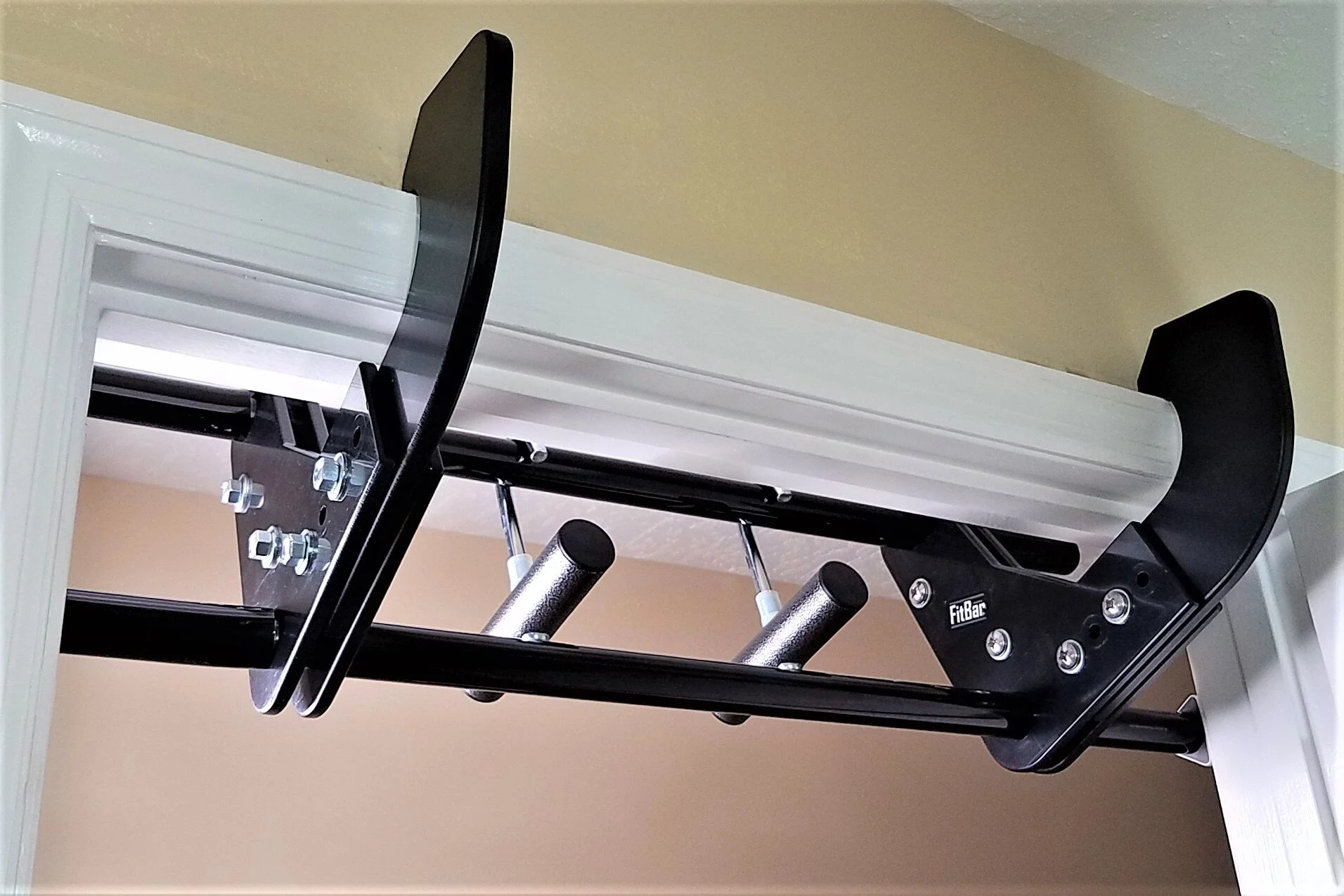 Close-up photo of a doorway pull-up bar hooks resting on a door frame trim, showing the contact points and stable placement