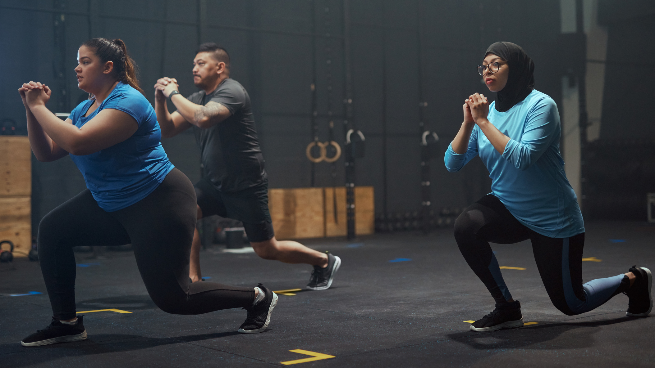 Close view of a person stepping one foot back into a reverse lunge with feet spaced hip-width apart for balance, shown on a hardwood floor