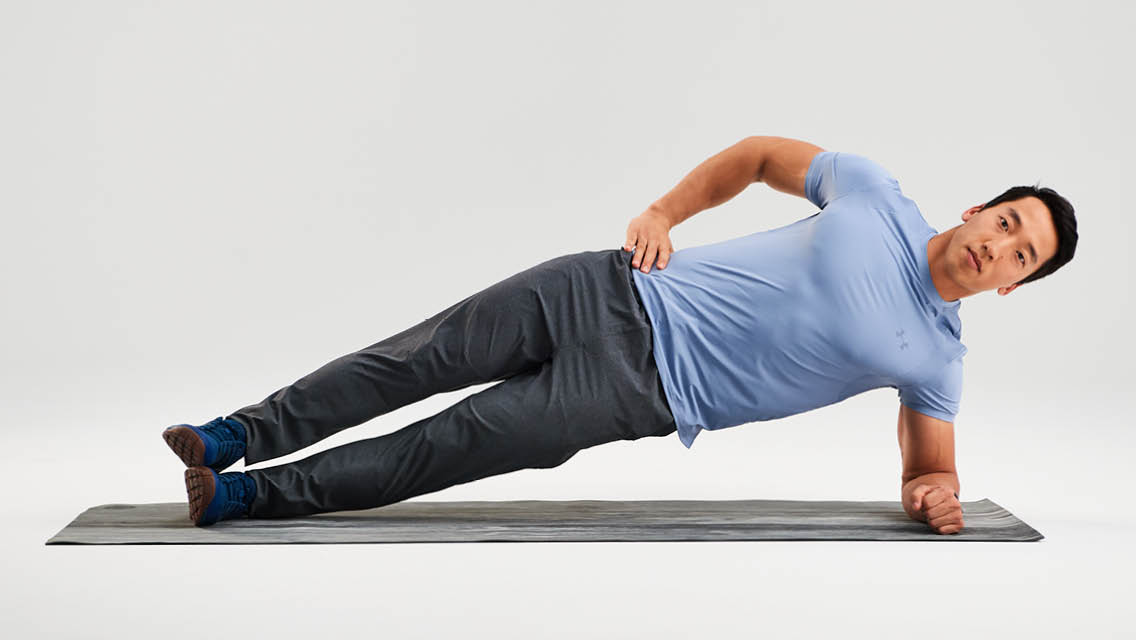 Person holding a forearm side plank with elbow under shoulder, body in a straight line, and hands relaxed while weight stays through the forearm and elbow
