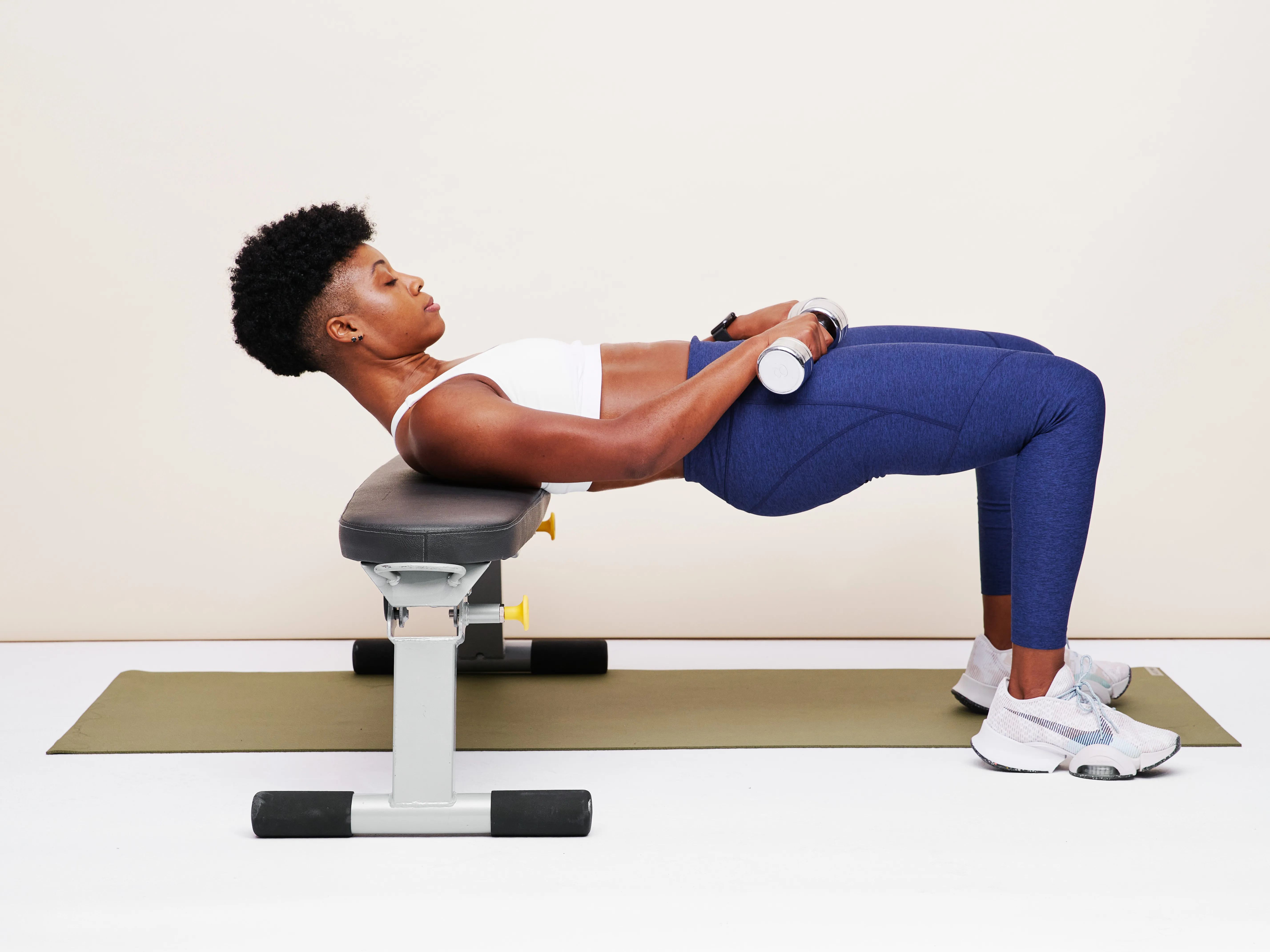 Person lying on their back with knees bent and feet flat, setting up for a glute bridge with arms resting by their sides